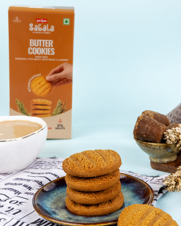 Millet Butter Cookies stack on blue plate with cup of tea and orange packaging in background