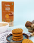 Millet Butter Cookies stack on blue plate with cup of tea and orange packaging in background