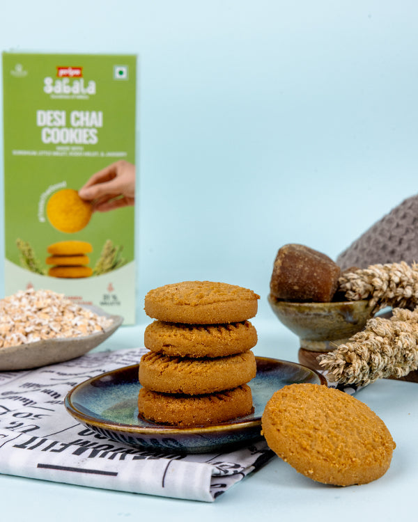 Stack of Millet Desi Chai Cookies on a plate with packaging and grains in the background