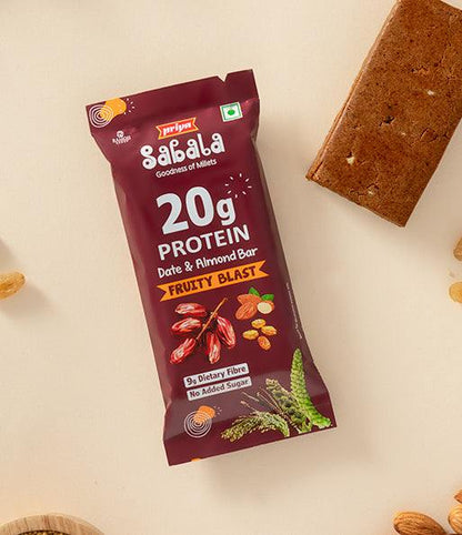Fruity Blast Date &amp; Almond Bar packaging with a protein and dietary fiber label alongside the unwrapped snack bar and almonds on a beige background