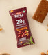 Fruity Blast Date & Almond Bar packaging with a protein and dietary fiber label alongside the unwrapped snack bar and almonds on a beige background