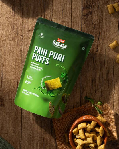 Green packaging of Pani Puri Puffs snack made with sorghum, pearl, and finger millet shown with bowl of crunchy puffs on wooden surface