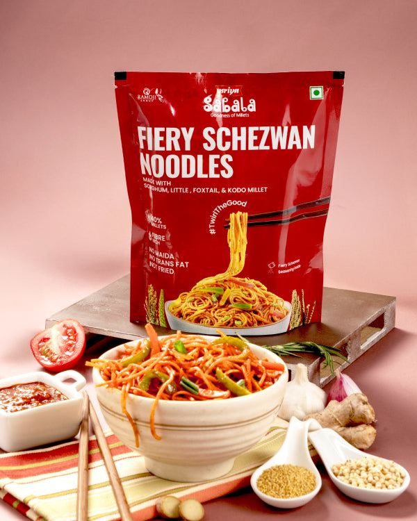 Millet Fiery Schezwan Noodles package with bowl of spicy Hakka noodles and fresh ingredients on table